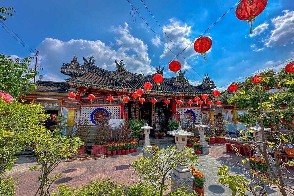 Front view of Kien An Cung Temple in Sa Dec, Dong Thap with lanterns, ornate roof, and flowering plants