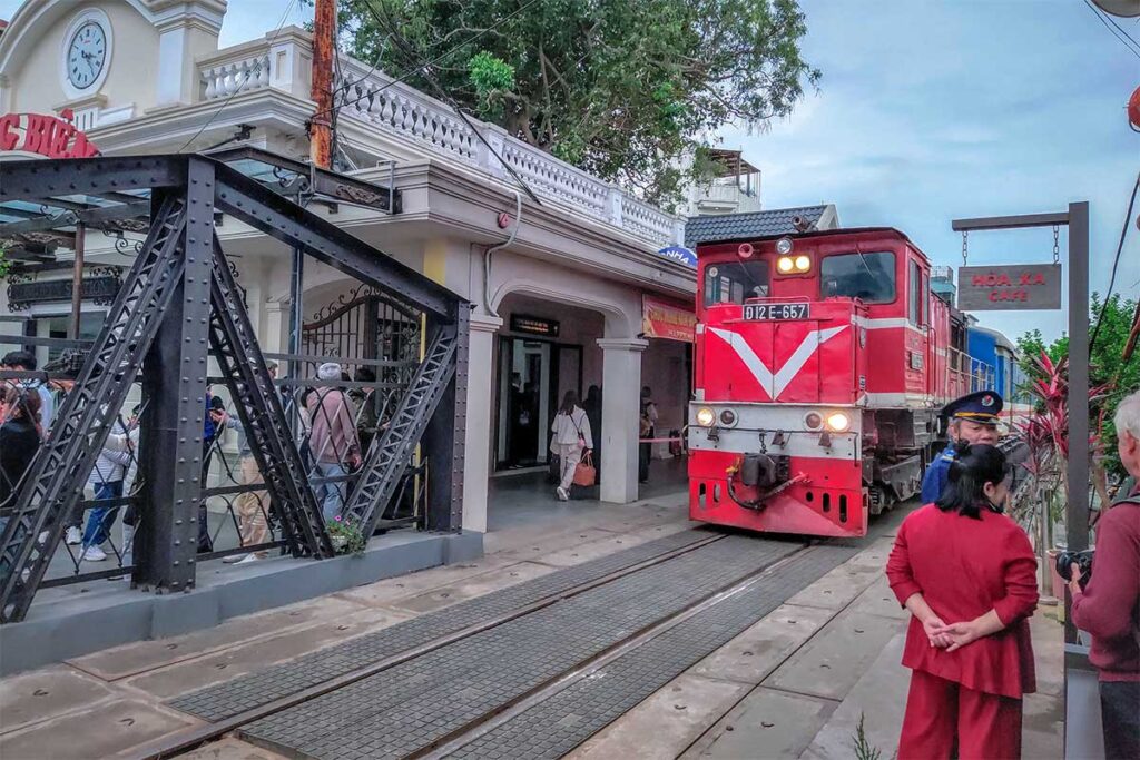 A train parked at the platform of Long Bien train station and people waiting to go to the platform
