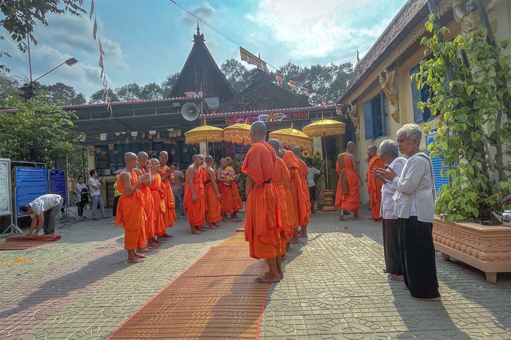 Group of Khmer monks in orange robes participating in a ceremony at Ang Pagoda in Tra Vinh, Vietnam.