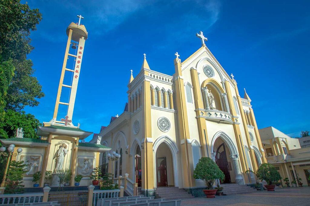 My Tho Cathedral with separate bell tower and statues, showing yellow and white colonial-era architecture.