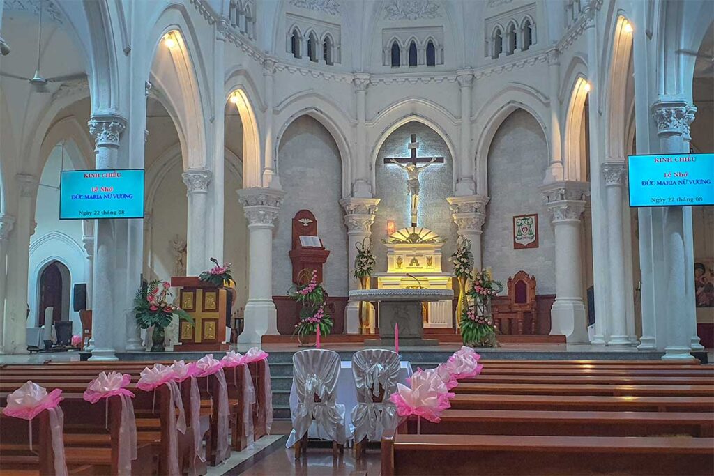 Interior view of My Tho Cathedral with pews, arched columns, and altar prepared for mass in Tien Giang, Vietnam.