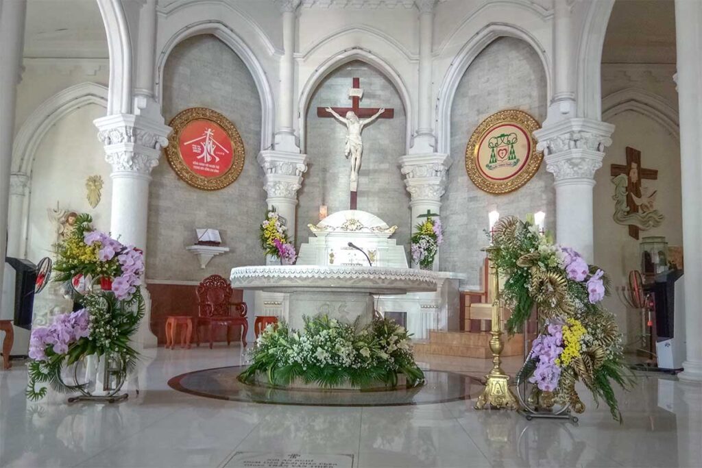 Altar inside My Tho Cathedral decorated with flowers, crucifix, and religious symbols in the main sanctuary.