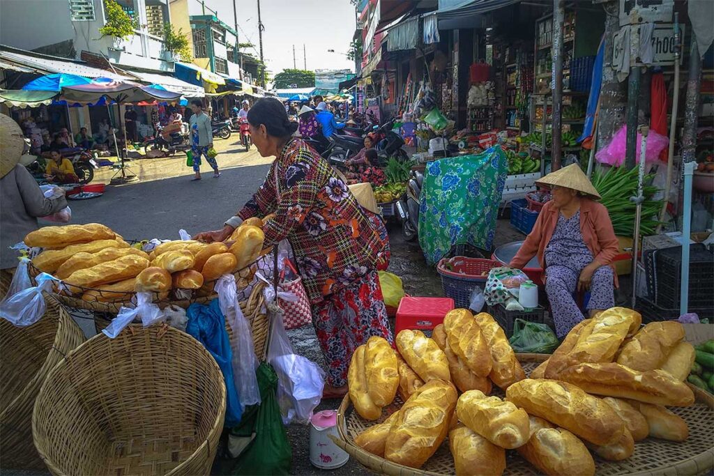 Street vendor selling fresh baguettes at My Tho Market in the Mekong Delta.