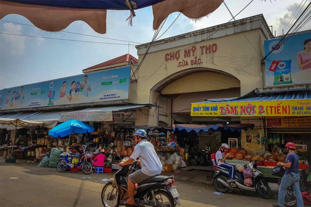 Front gate of My Tho Market with motorbikes and shops in Tien Giang Province