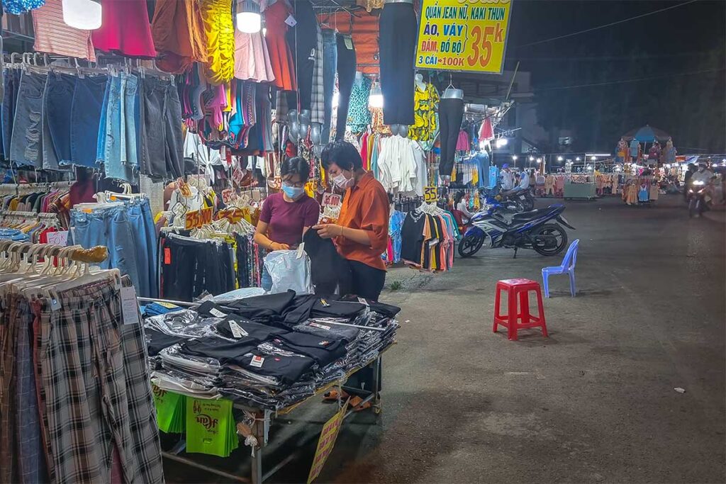 Clothing stalls at My Tho Night Market with locals shopping in the evening.