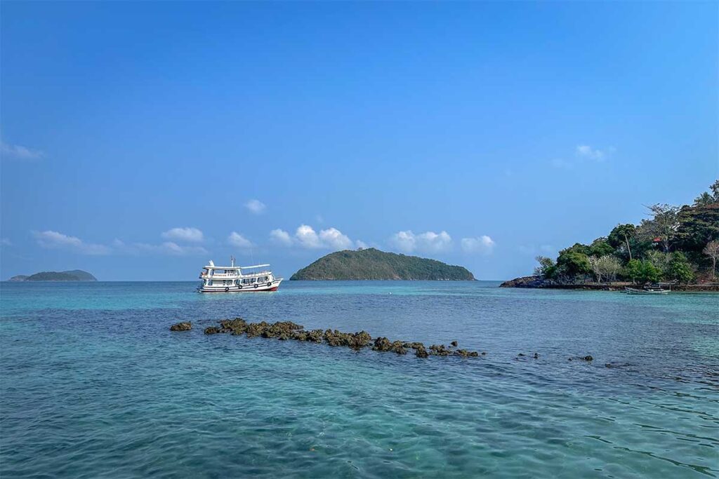 Boat trip near Hon Dau Islet – Tour boat anchored in clear shallow water, a popular stop on Nam Du island-hopping tours.