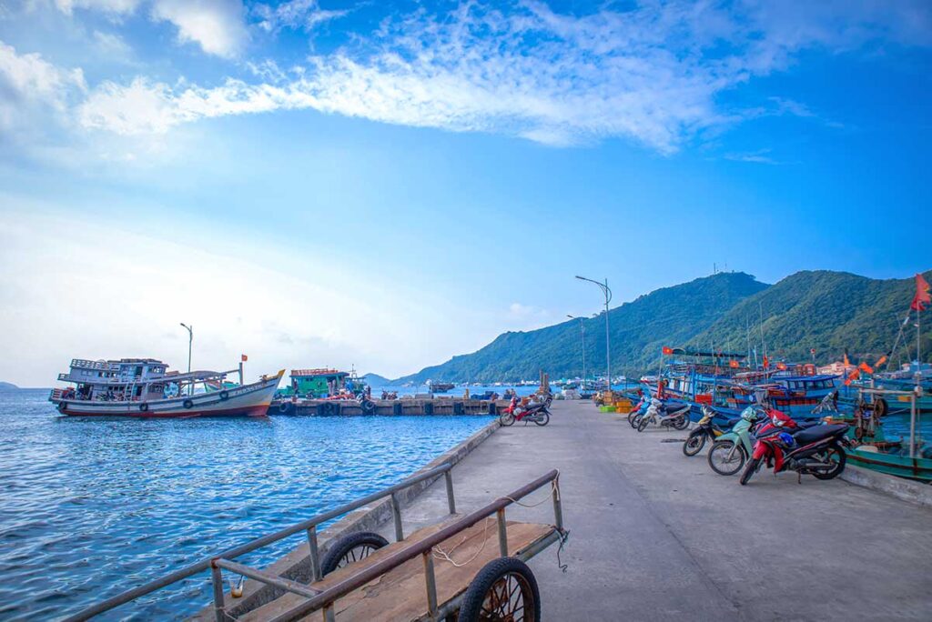 Nam Du Wharf with fishing boats and motorbikes – Busy pier on Nam Du Island where ferries and wooden fishing boats dock, gateway for travelers arriving from Rach Gia.