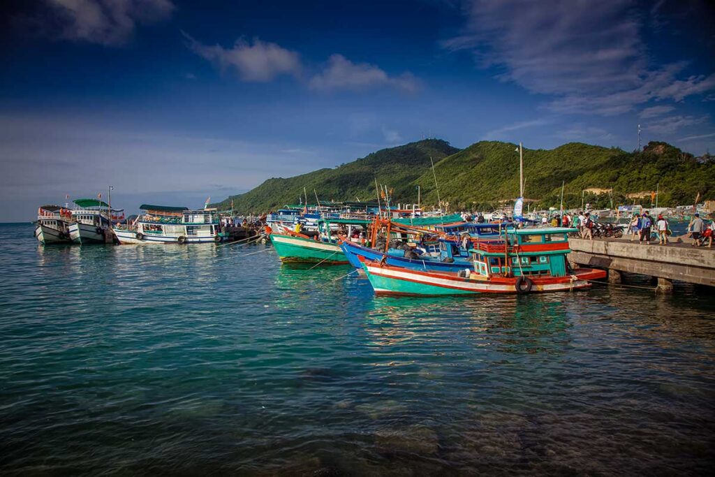Fishing boats at Nam Du Wharf – A cluster of vibrant fishing boats tied up at the main Nam Du pier with green hills in the background.