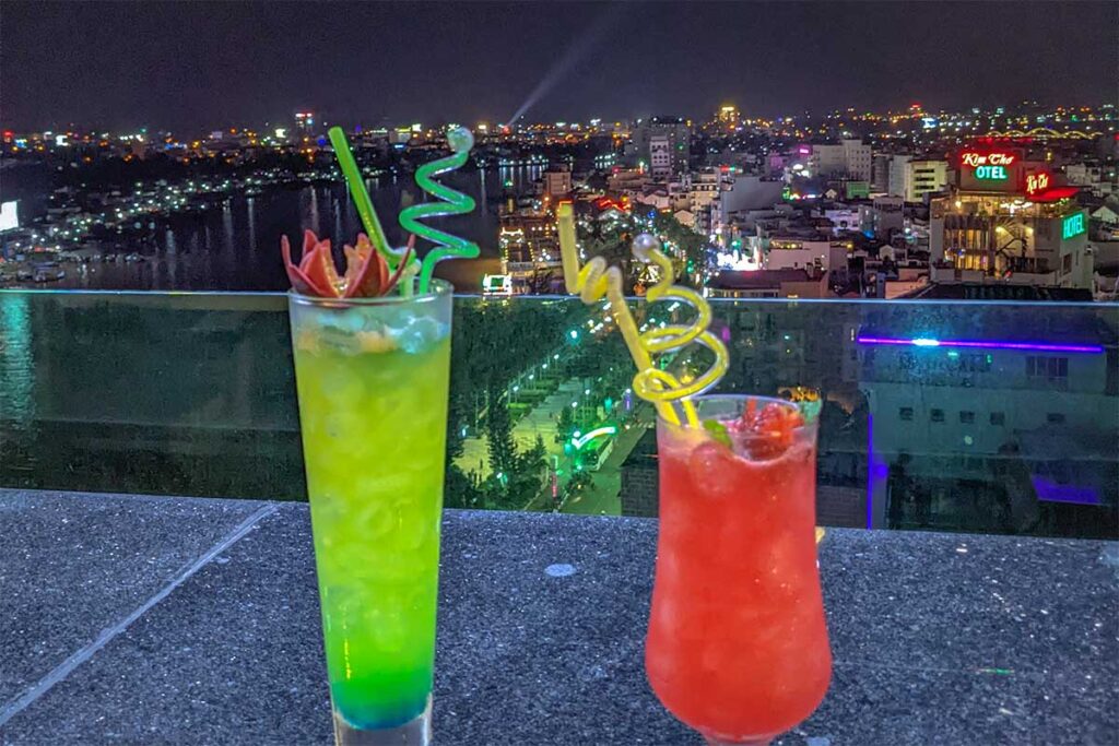 Two colorful cocktails on Ninh Kieu Sky Bar overlooking Ninh Kieu Wharf from above in the late evening