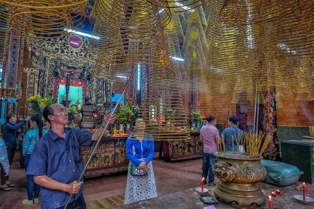 Locals hanging long incense on the ceiling of Ong Pagoda in Can Tho 