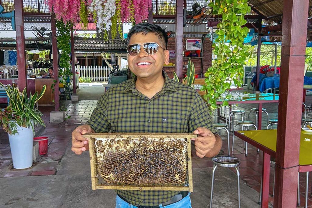 Visitor holding a honeycomb frame during a beekeeping and honey-tasting activity on Phoenix Island.