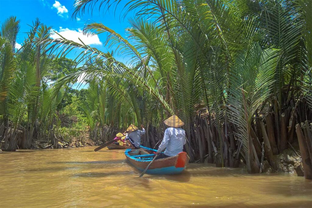 Tourists on a sampan ride under nipa palms on Phoenix Island, Ben Tre, Vietnam.
