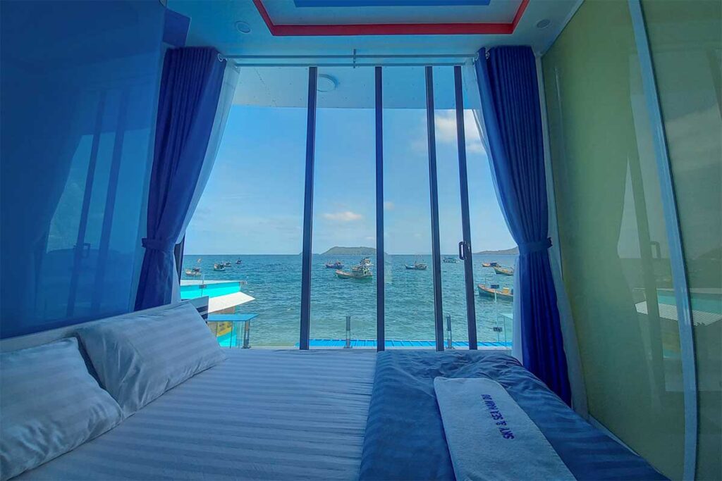 The hotel bedroom of Sky & Sea Nam Du with bed and view through the windows of the ocean 