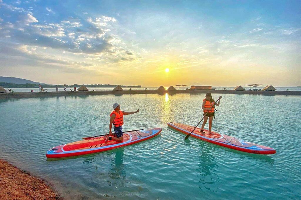 Two Vietnamese travellers are supping on Dau Tien Lake during sunset