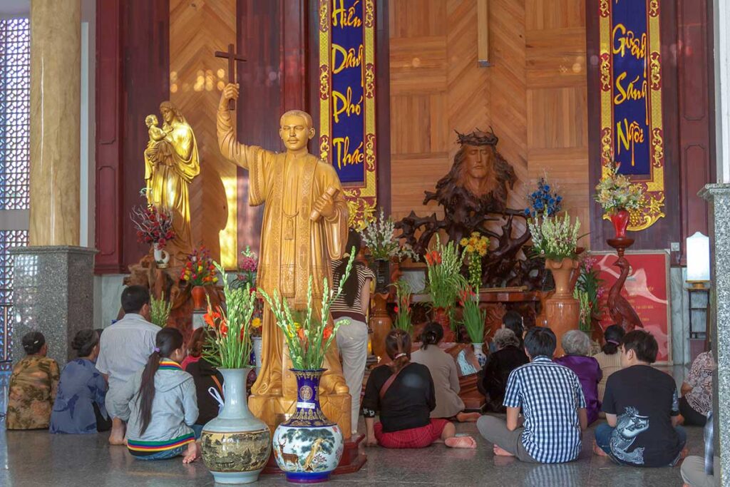 People praying at a statue of Father Truong Buu Diep at PTac Say pilgrimage Center