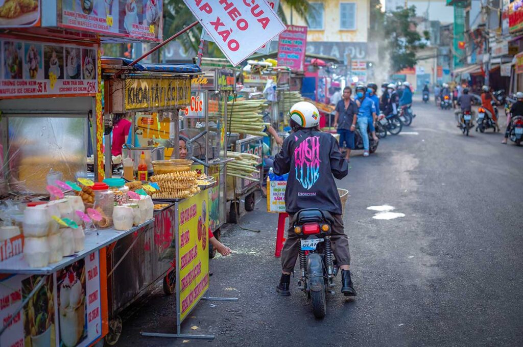 A woman on a motorbike stopped at a street food stall on Tay Do Night Market in Can Tho