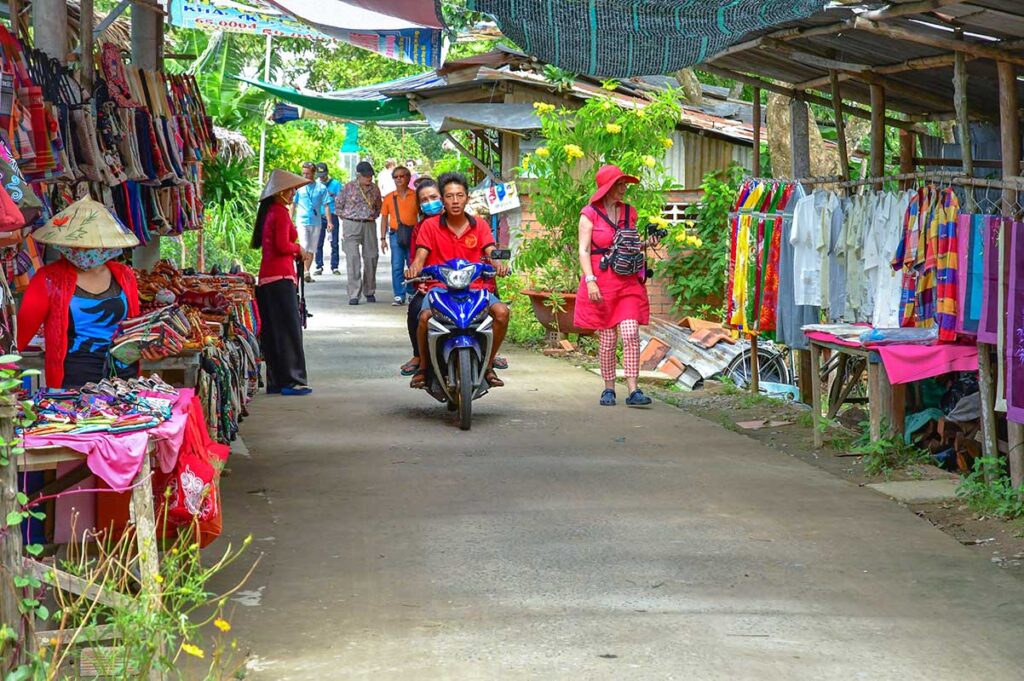 Souvenir street market on Unicorn Island (Thoi Son) where tourists browse handicrafts and textiles in the Mekong Delta.