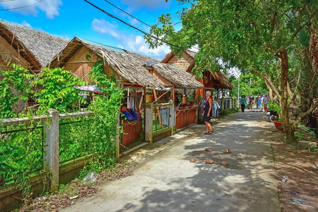 Leafy walking path with thatched souvenir stalls on Unicorn Island (Thoi Son), a common stop for Mekong Delta tours.