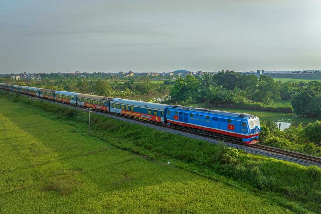 The Reunification Express Train of Vietnam rides through the countryside of Quang Binh with green rice fields