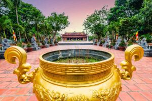 Golden incense urn in the courtyard of Truc Lam Phuong Nam Zen Monastery in Can Tho with the main hall in the background.