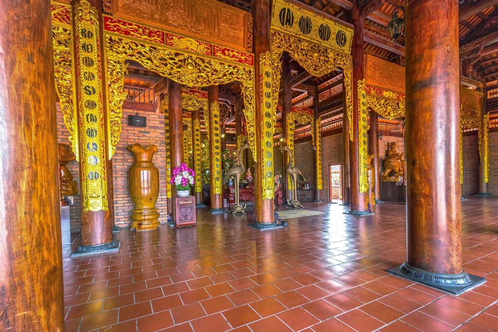 Main hall interior of Truc Lam Phuong Nam Zen Monastery in Can Tho with ironwood pillars and golden carvings.