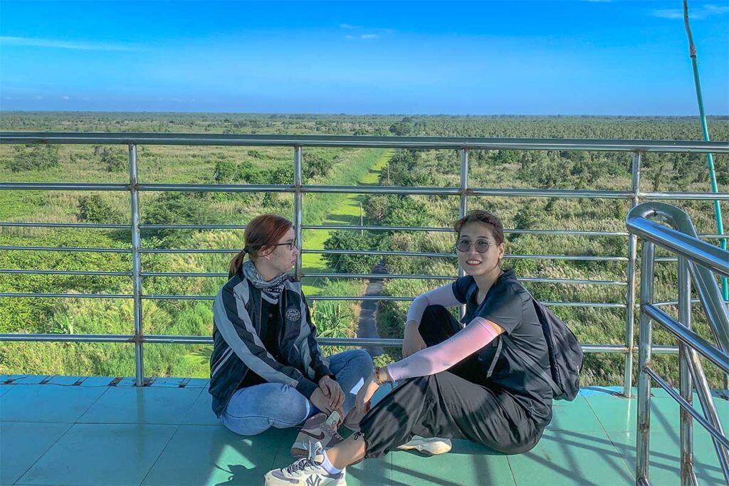 Two Vietnamese travellers sittin on the oversation tower that overlooks U Minh Ha National Park