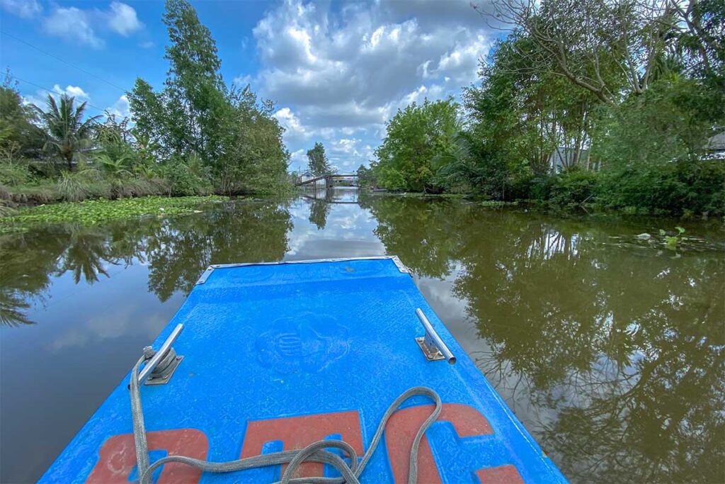 Boat ride along tea-colored canals surrounded by trees inside U Minh Thuong National Park.
