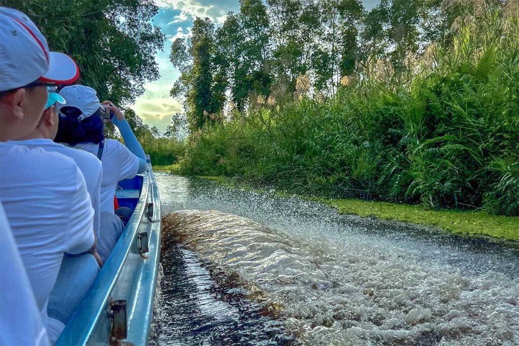 Tourists on a motorboat navigating through the canals of U Minh Thuong National Park.