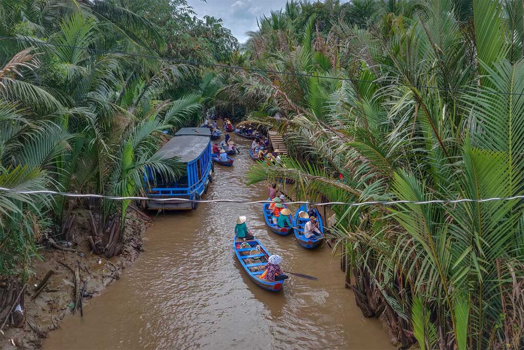 Small sampan boats paddling through nipa palm canals on Unicorn Island, a popular tourist activity near My Tho.