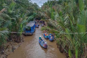 Small sampan boats paddling through nipa palm canals on Unicorn Island, a popular tourist activity near My Tho.