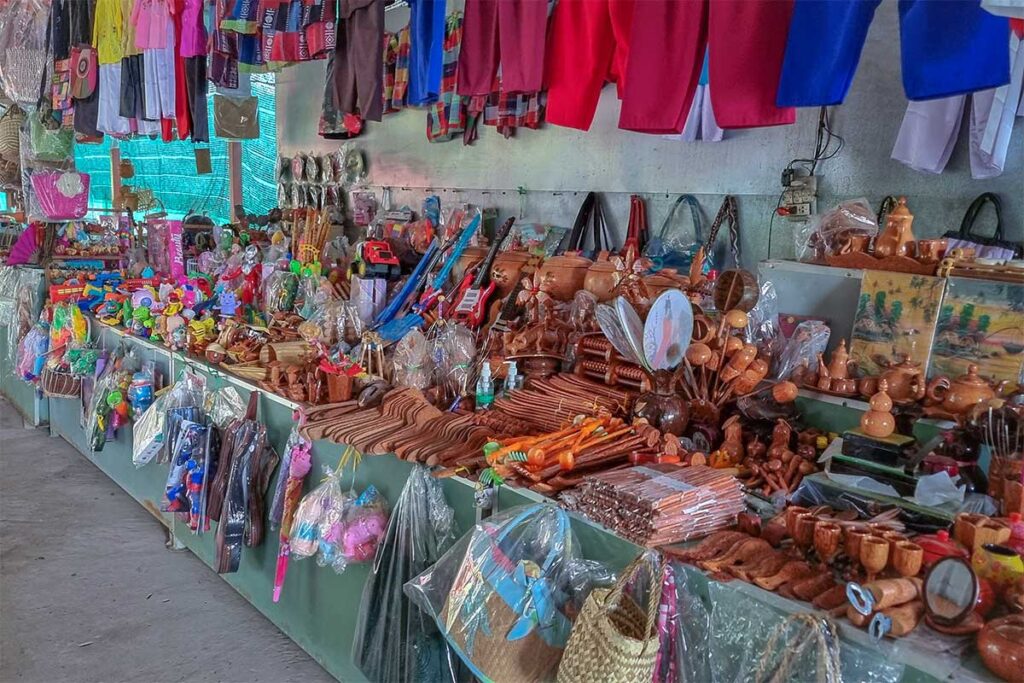 Souvenir stall on Unicorn Island selling handicrafts, wooden toys, and colorful fabrics to Mekong Delta visitors.
