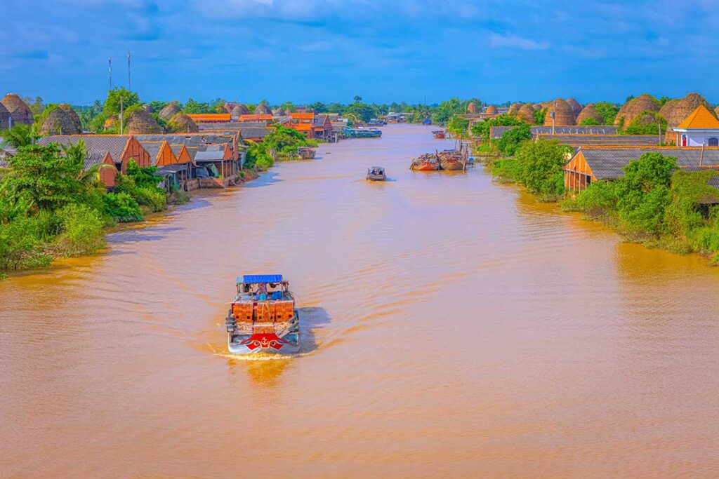 Cargo boat carrying bricks along the river past Mang Thit kilns in Vinh Long