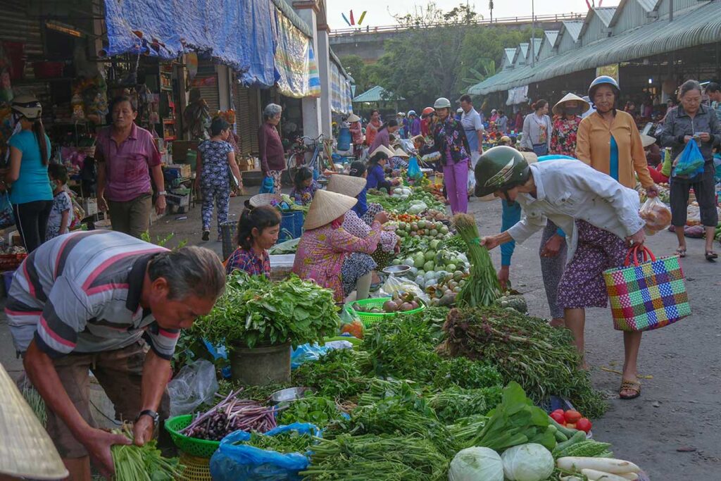 Vendors at An Binh Market in Can Tho selling fresh vegetables and herbs in an outdoor setting
