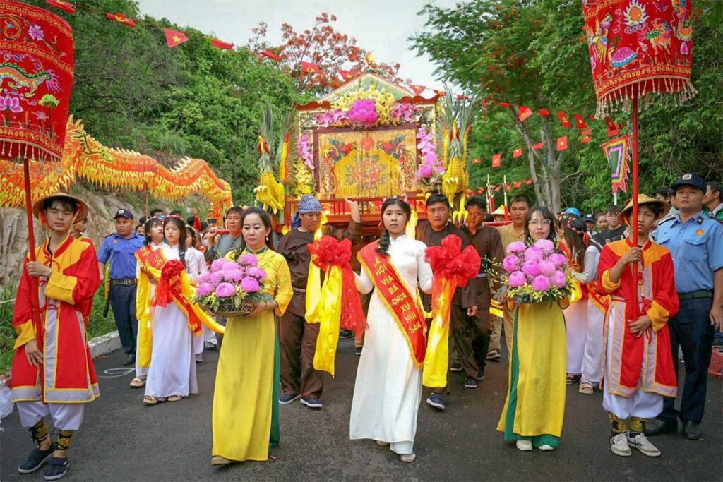 Procession at Ba Chua Xu Festival on Sam Mountain, Chau Doc, with women in traditional ao dai carrying offerings and a decorated palanquin.
