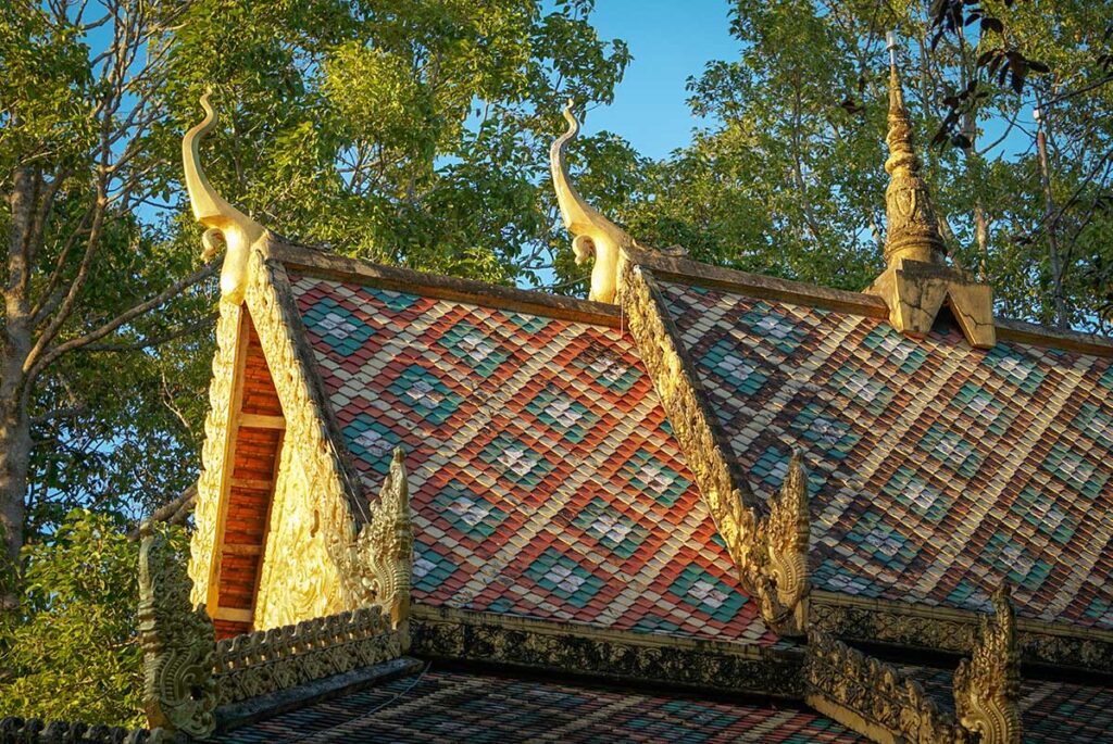 Close-up of the tiled roof of Bat Pagoda (Chùa Dơi) in Soc Trang with colorful patterns and golden naga ornaments.