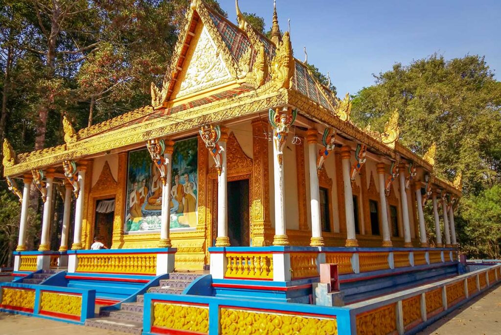 Main hall of Bat Pagoda (Chùa Dơi) in Soc Trang with Khmer architectural details, naga roof corners, and painted Buddha murals.