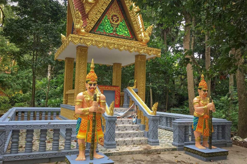Small shrine at Bat Pagoda (Chùa Dơi) in Soc Trang guarded by colorful Khmer warrior statues in the temple garden.