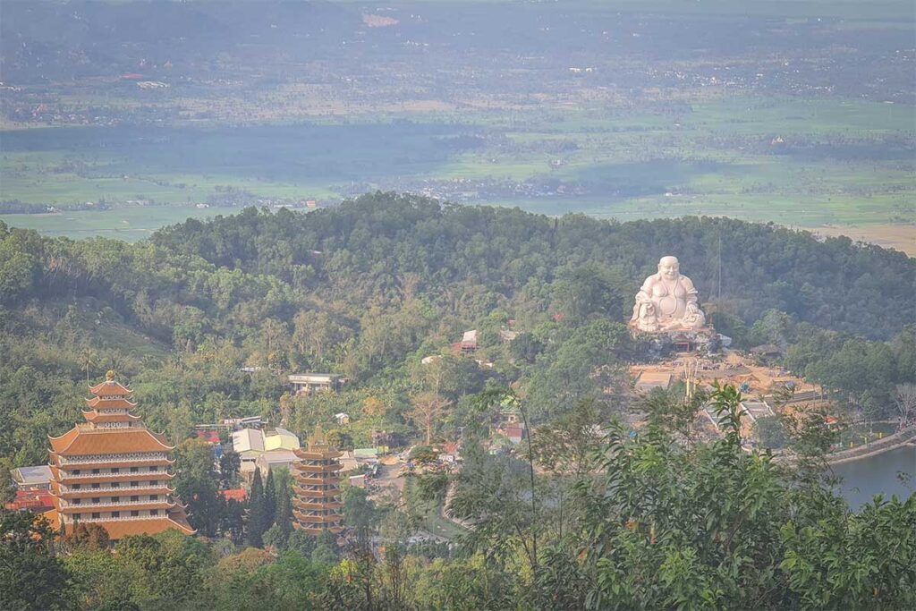 View from Bo Hong Peak on Cam Mountain, showing the giant Maitreya Buddha statue, Van Linh Pagoda, and surrounding rice fields in An Giang.