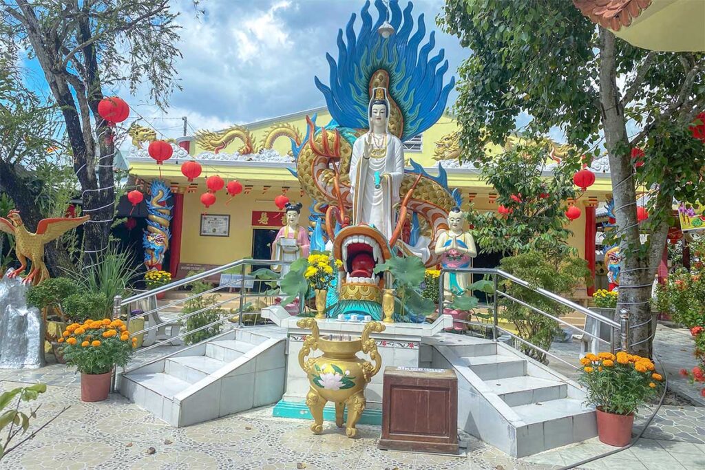 Guanyin statue with dragon backdrop at Clay Pagoda – White Guanyin standing on a lotus with a dramatic dragon and flame background in the courtyard.