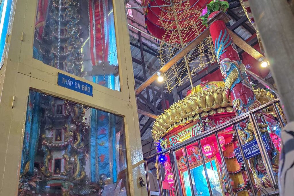 Close-up of Da Bao Tower in Clay Pagoda, showing intricate clay carvings, miniature Buddhas, and protective glass case in the temple interior.