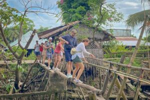 Tourists crossing a bamboo monkey bridge on Con Son Islet, a rustic rural experience in Can Tho