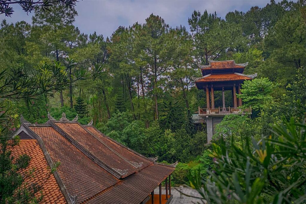Open-sided Nghinh Luong Dinh pavilion at Huyen Khong Son Thuong Pagoda in Hue, a wooden rest house with tiled roof overlooking the main hall and forested hills.