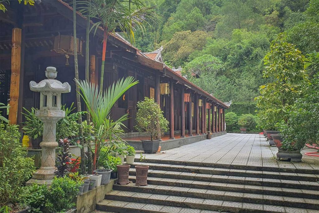 View of the wooden prayer hall and tiled courtyard surrounded by forest at Huyen Khong Son Thuong Monastery in Hue’s hills.