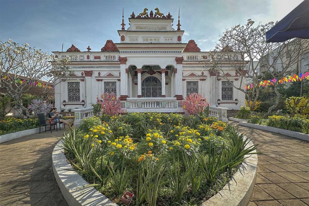Front facade of Huynh Ky Ancient House in Tra Vinh, built in 1924, with colonial architecture and flower garden.