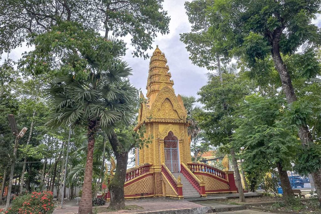 Golden Khmer-style entrance gate of Kh’leang Pagoda in Soc Trang, decorated with red details and guardian figures.