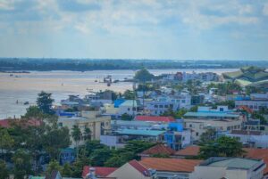 Long Xuyen city view with Hau River in the background – Panoramic view of Long Xuyen, An Giang, showing riverside houses, modern buildings, and boats along the Hau River.