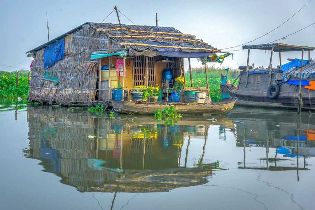 Floating house on Hau River in Long Xuyen – Traditional stilt-and-thatch floating house with small boat, reflecting daily river life in the Mekong Delta.