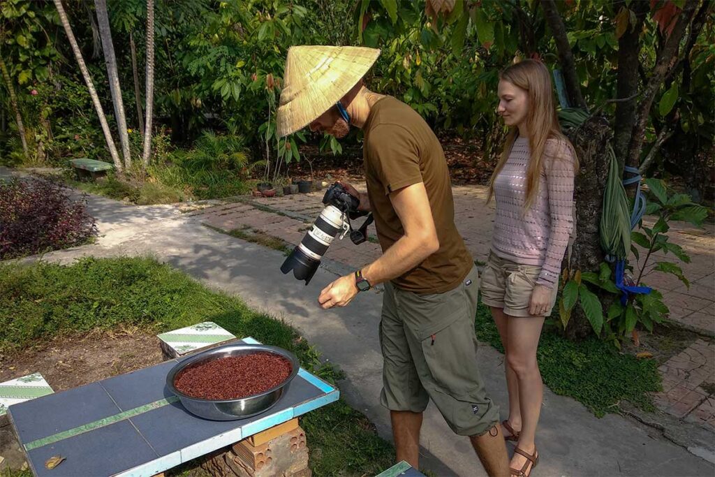 Tourists photographing roasted cacao nibs at Muoi Cuong Cacao Farm in Can Tho