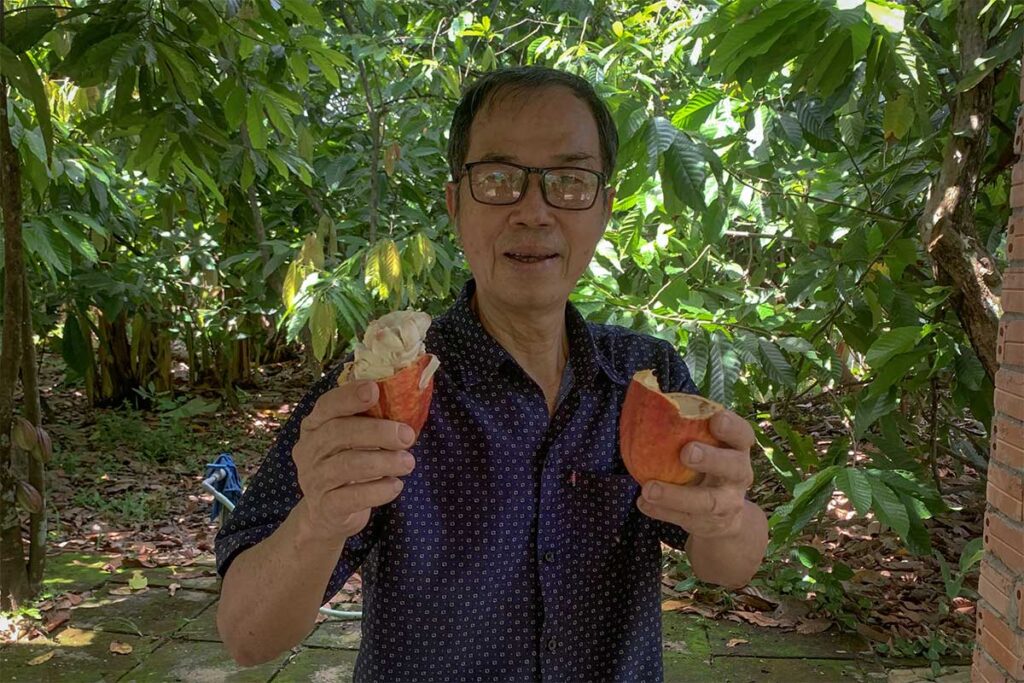 Mr. Cuong holding a freshly opened cacao pod at Muoi Cuong Cacao Farm in Can Tho