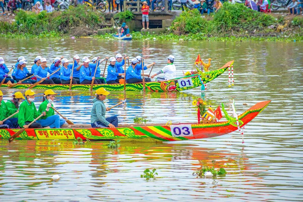 Women’s rowing teams in green and blue competing in the Ghe Ngo Boat Race Festival in Soc Trang, paddling brightly decorated Khmer boats.